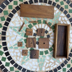 Obiettivo del gioco Il blocco quadrato più grande (quello in alto a sinistra con i quattro pallini blu) rappresenta il prigioniero o il pezzo principale. L'obiettivo consiste nel muovere e far scorrere i vari blocchi di legno all'interno della scatola fino a far uscire il quadrato grande attraverso la fessura situata sul lato inferiore della cornice. [1, 2, 3] Caratteristiche principali * Meccanica: Si tratta di un rompicapo sequenziale a blocchi scorrevoli; i pezzi possono essere spostati solo in orizzontale o in verticale sfruttando i due spazi vuoti. [1, 2] * Configurazioni: La scatola permette di impostare fino a 16 diverse combinazioni iniziali con livelli di difficoltà variabili (da medio a estremo). [1, 2] * Materiale: È tipicamente realizzato a mano in legno di Teak o suar.